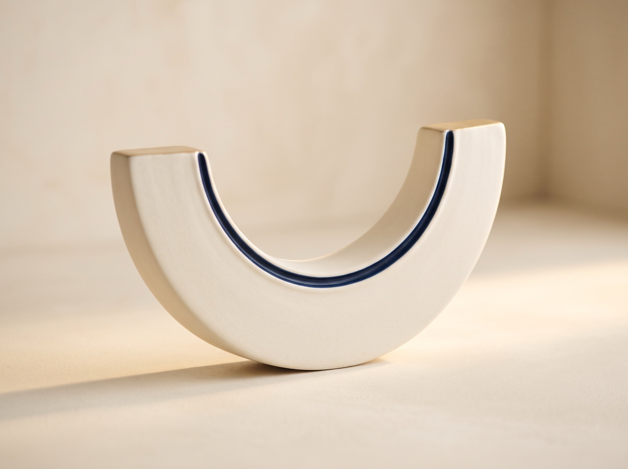 Ceramic arch sculpture with a navy inner rim, echoing a smile